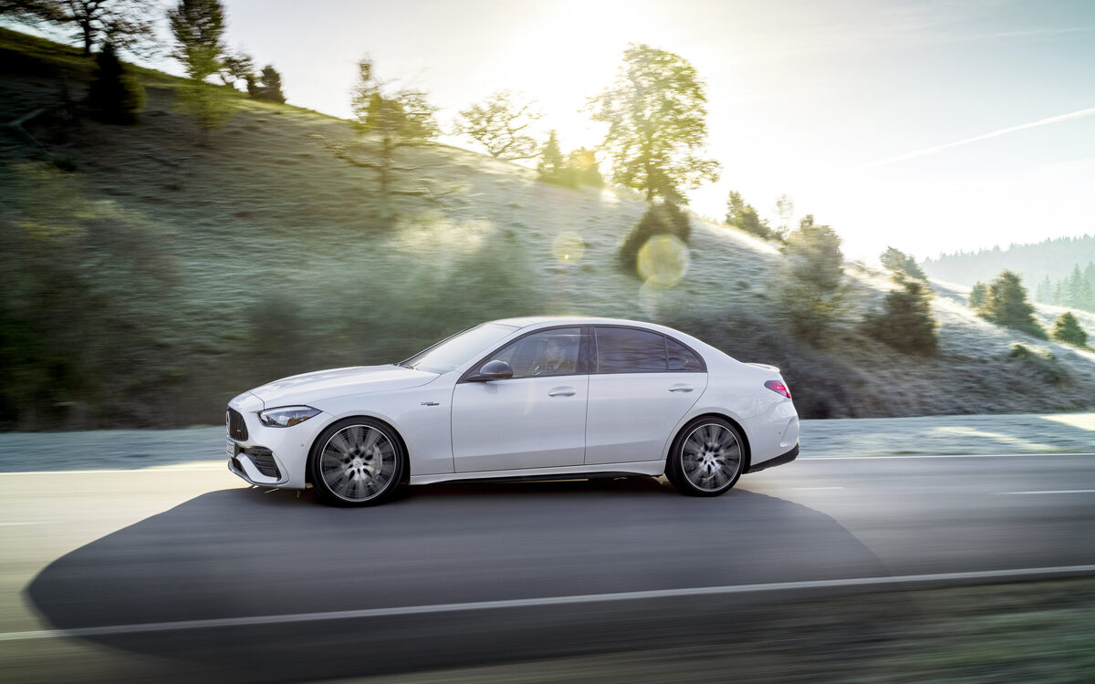 Mercedes-AMG C 43 in Opalite White on a hillside road in low sun, side profile