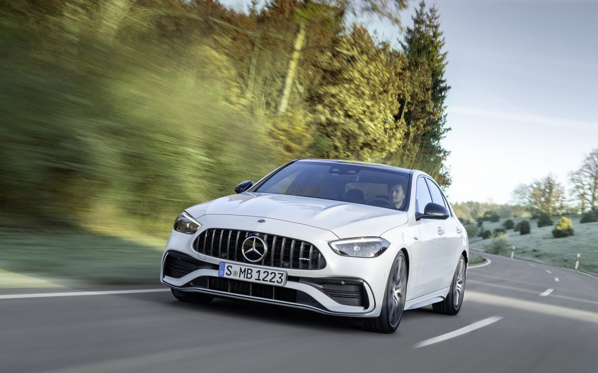Mercedes-AMG C 43 in Opalite White driving towards the camera, showing the AMG grille