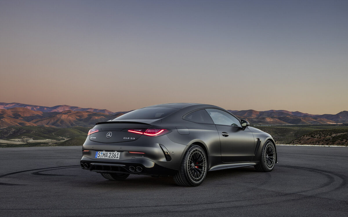 Mercedes-AMG CLE 53 Coupé in matte grey on tarmac at dusk, rear three-quarter view with red tail lamps lit