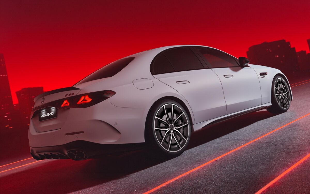 Mercedes-AMG E 53 Hybrid in silver-white, rear three-quarter view on a red-lit night road