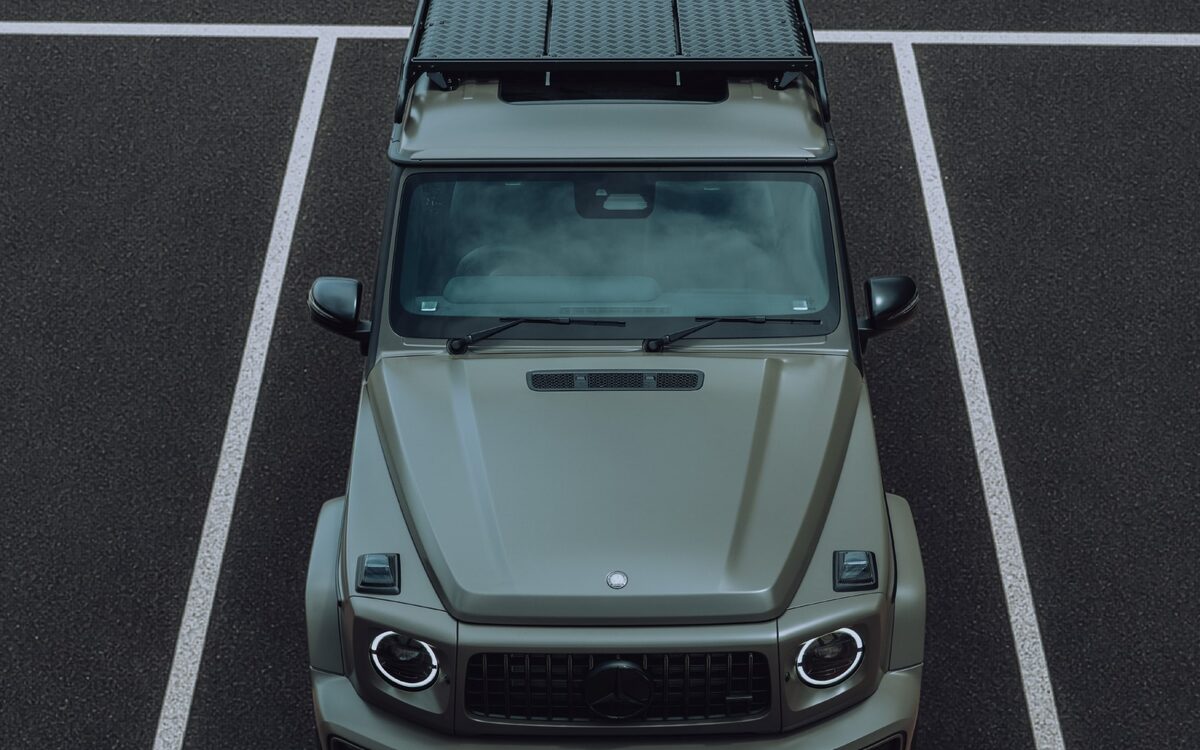 Mercedes-AMG G 63 in grey-green with a roof luggage rack, seen from above in a parking bay