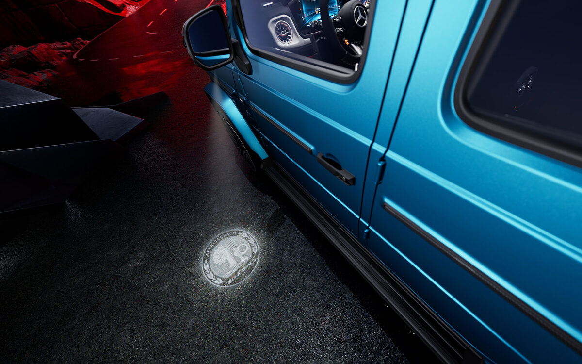 Blue G 63 with the Mercedes-AMG star projected on the ground from the door entry light