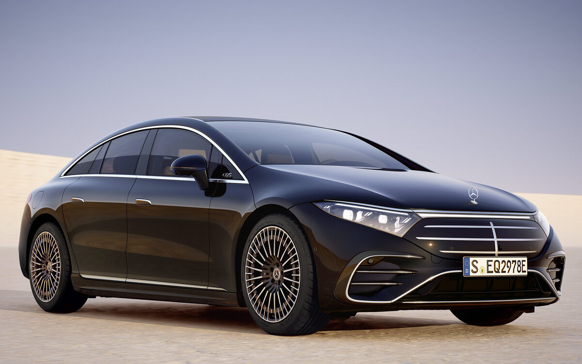 Mercedes-Benz EQS in black parked on sand with a blue sky behind, front three-quarter view