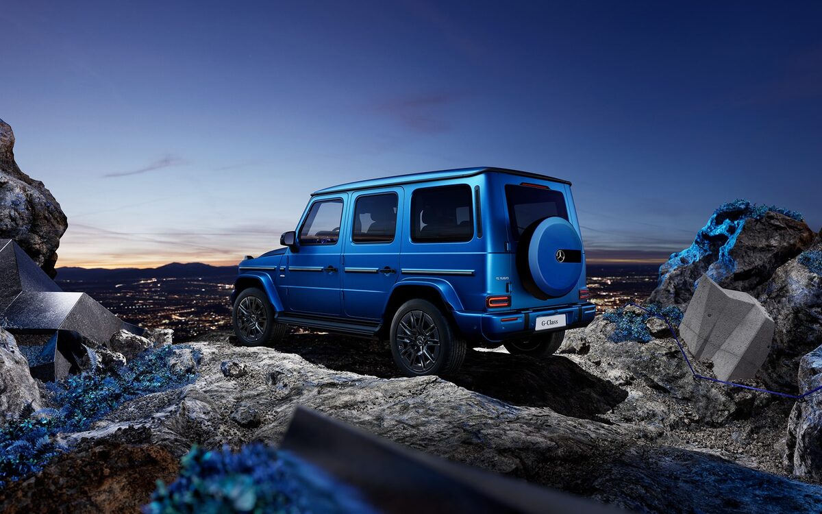 Blue G 580 with EQ Technology seen from the rear three-quarter on a rocky trail with a city in the background