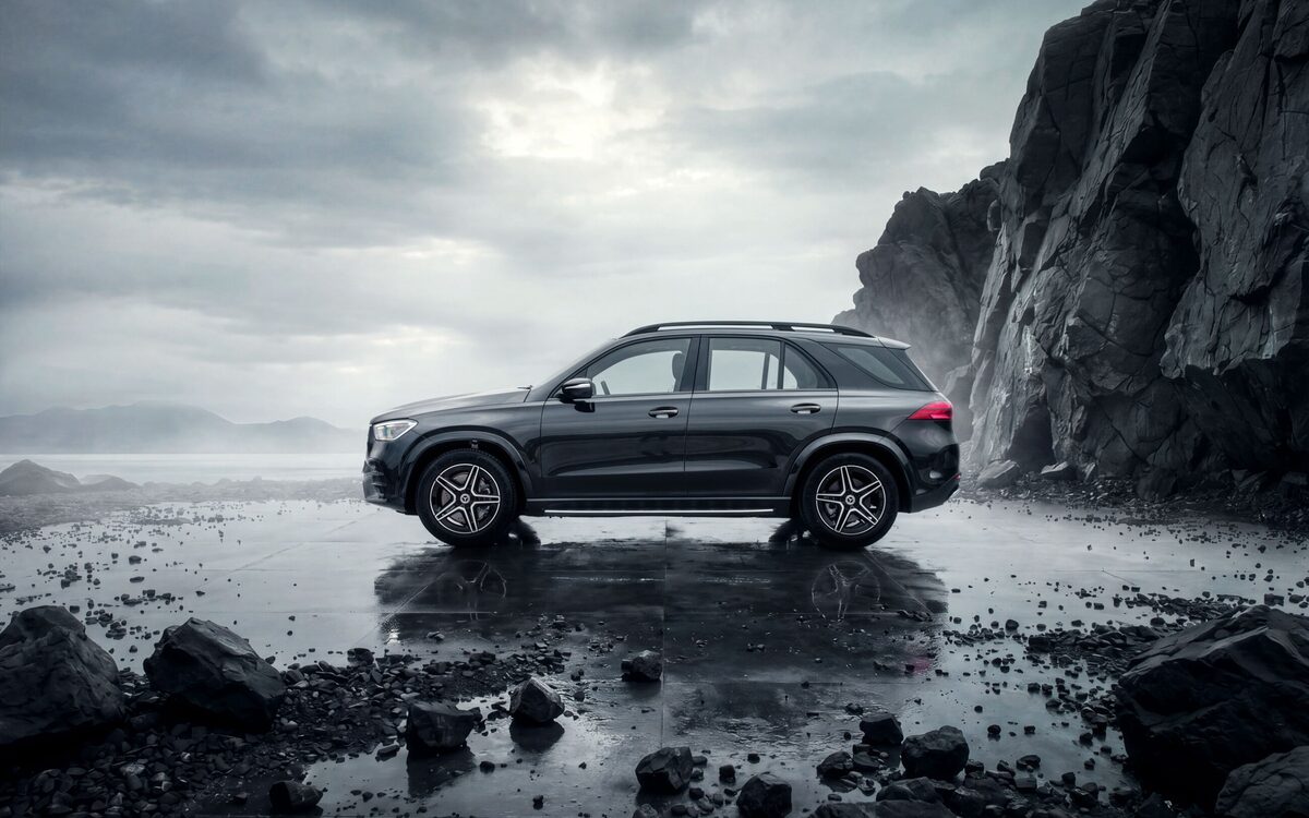 Mercedes-Benz GLE in dark grey parked on a wet rocky shore under a stormy sky