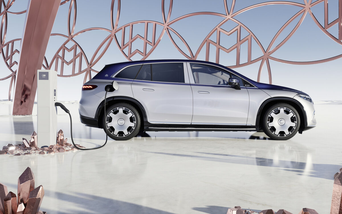 Mercedes-Maybach EQS SUV in silver and blue, side view while plugged in to a charger