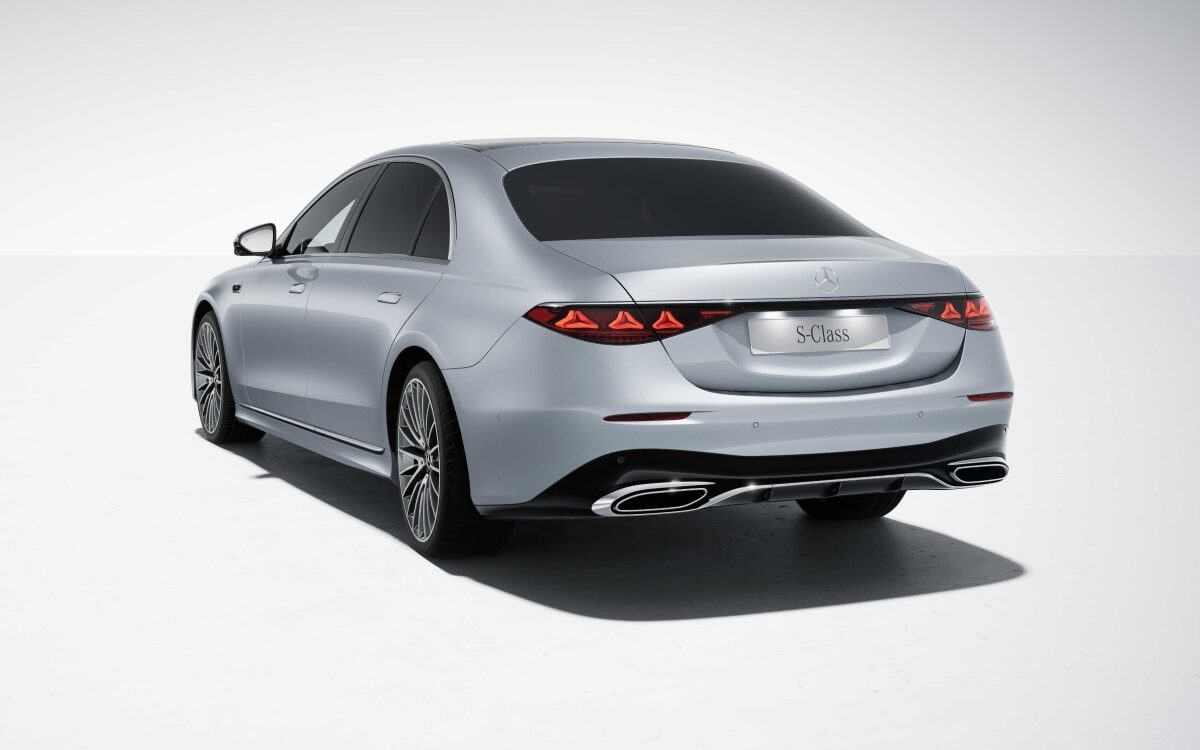 Silver Mercedes-Benz S-Class seen from the rear three-quarter with the split LED tail lamps, on a white studio floor