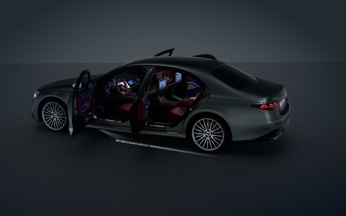 Dark green Mercedes-Benz S-Class in a dark studio with all four doors open showing the red leather cabin