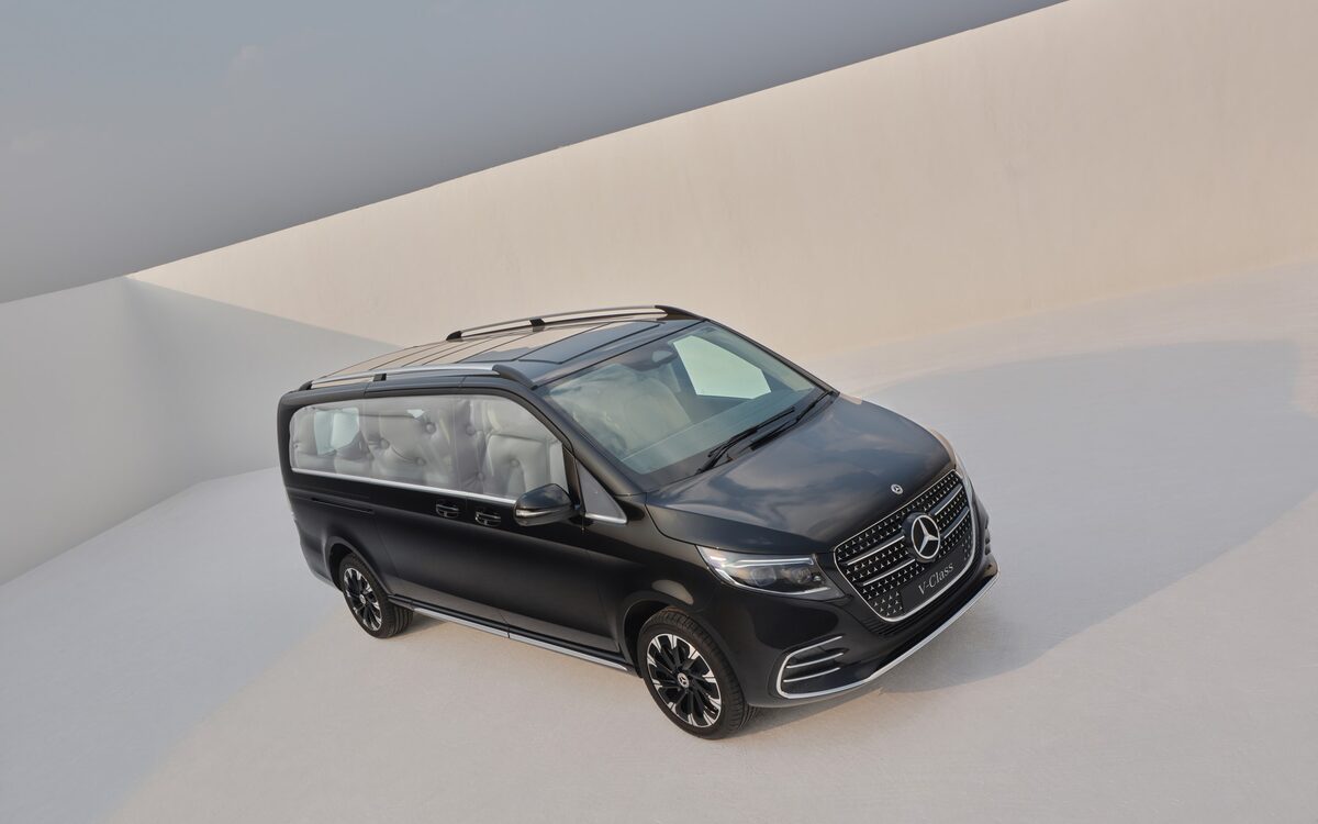 Black Mercedes-Benz V-Class seen from above and the front corner in a pale curved studio