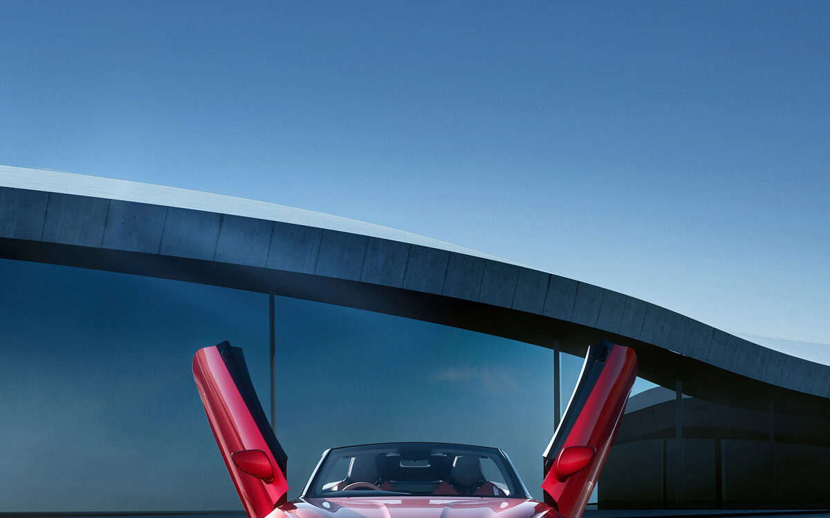 MG Cyberster in red, seen from the front with both scissor doors raised beside a curved building