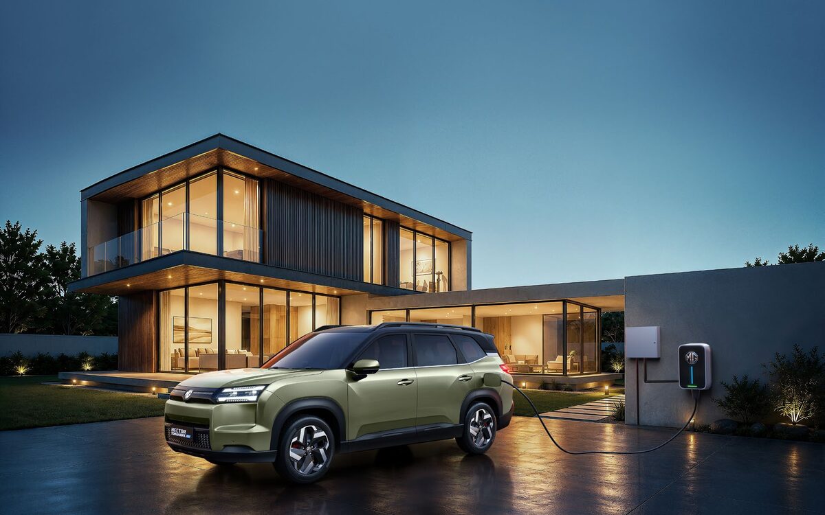 MG Hector Tomahawk EV in khaki green parked outside a modern house beside a wall charger at dusk