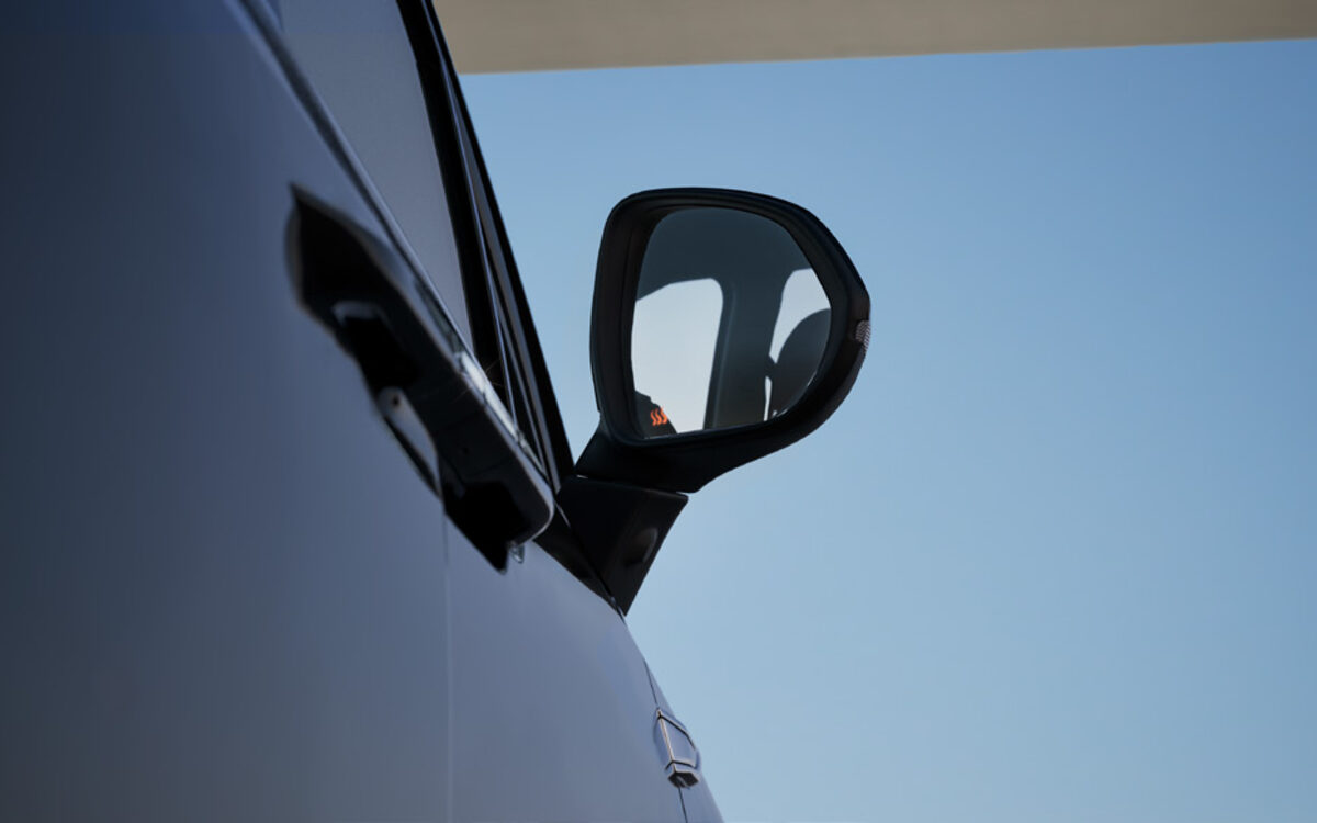 Close-up of the MG M9 door mirror and flush door handle against a blue sky