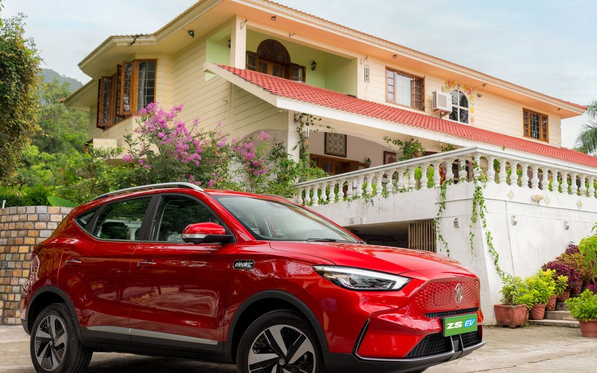 MG ZS EV in red parked in front of a house, front three-quarter view