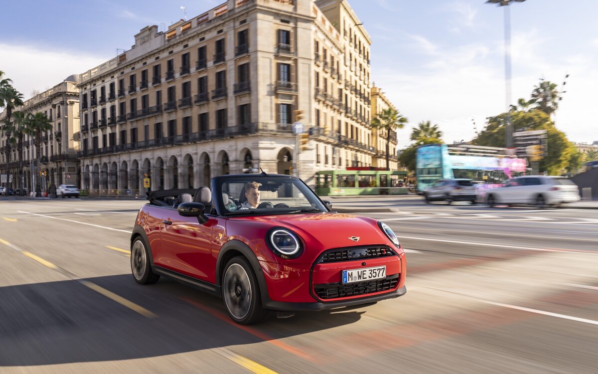MINI Cooper Convertible S in red with the roof down, front three-quarter view in the city