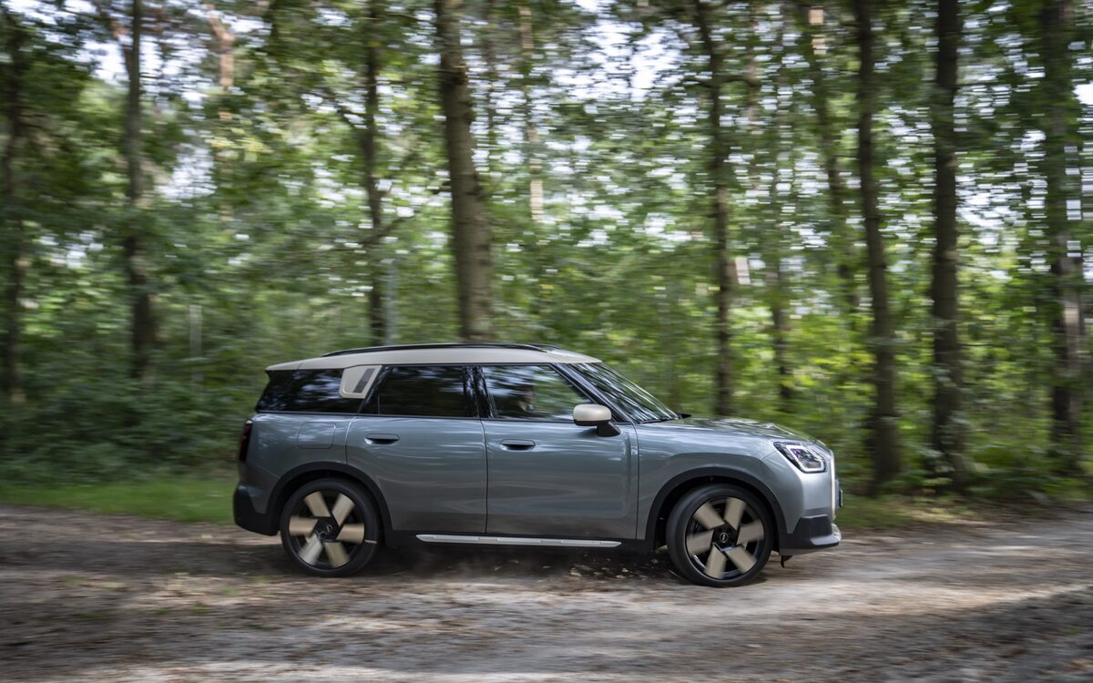 MINI Countryman in grey driving on a forest track, side profile