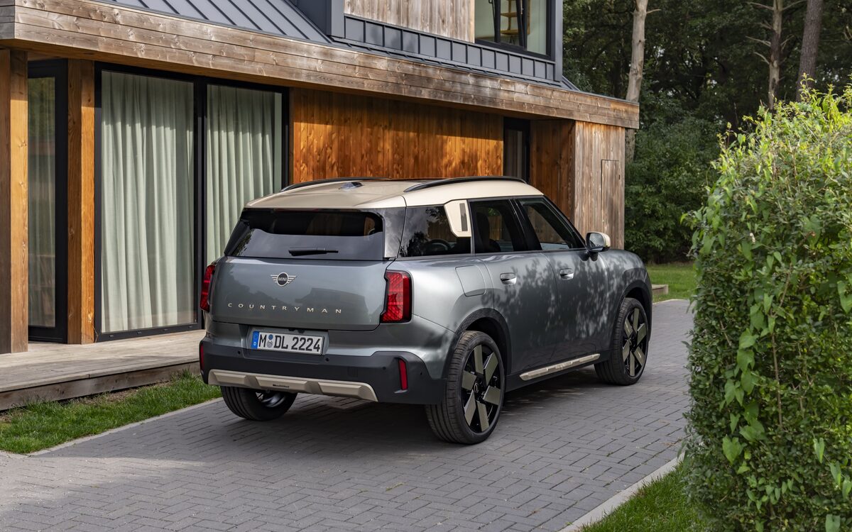 MINI Countryman in grey, rear three-quarter view outside a wooden house