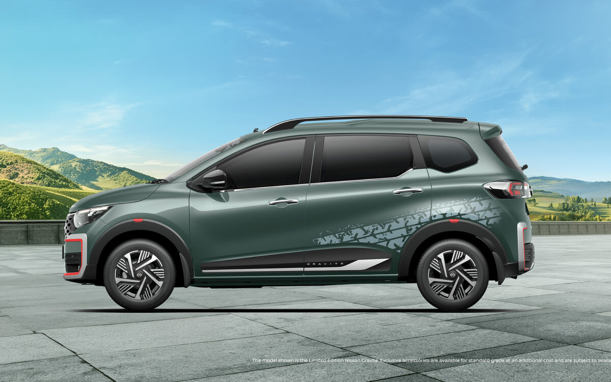 Nissan Gravite in green, side profile on a paved plaza with hills behind
