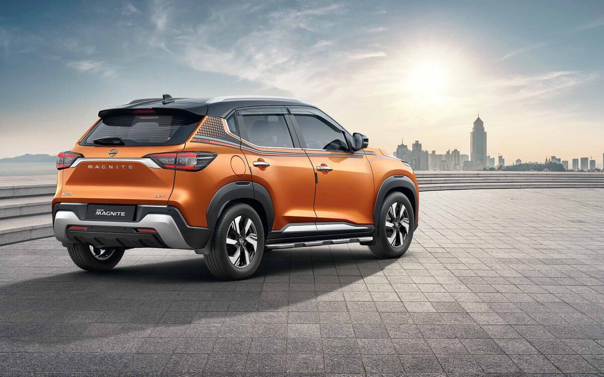 Nissan Magnite in orange, rear three-quarter view on a paved plaza at sunset