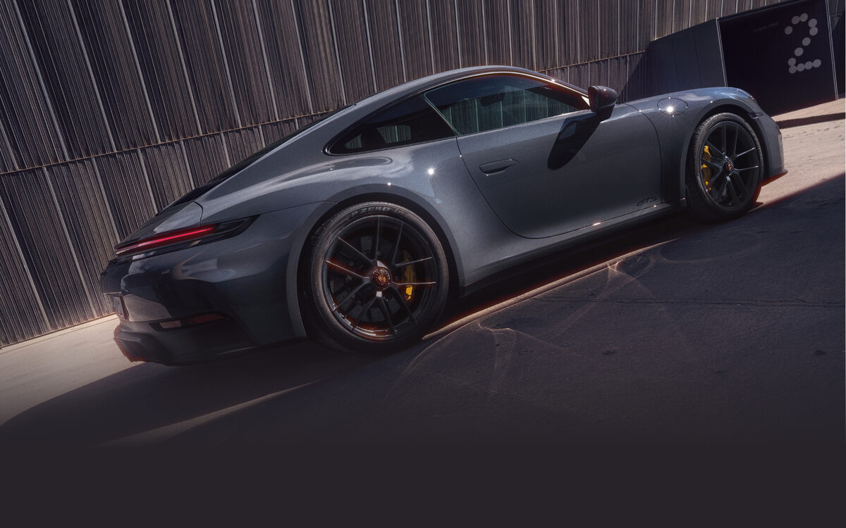 Porsche 911 in grey seen from the rear three-quarter on a dark ramp, red light strip glowing