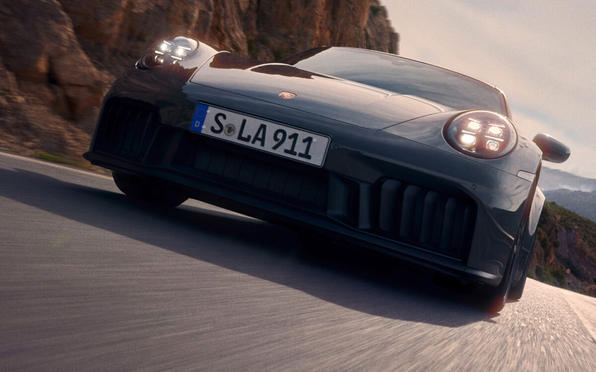 Porsche 911 driving up a mountain road towards the camera, shot from a low angle