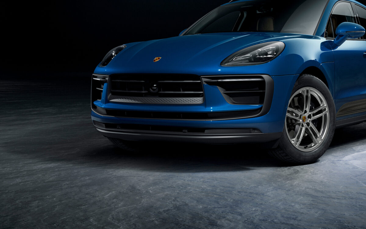 Blue Porsche Macan, front three-quarter view in a dark studio