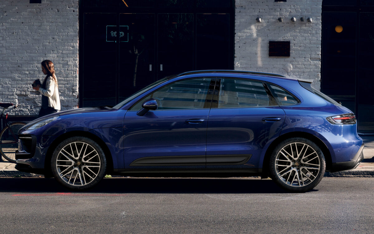 Blue Porsche Macan in side profile on a city street