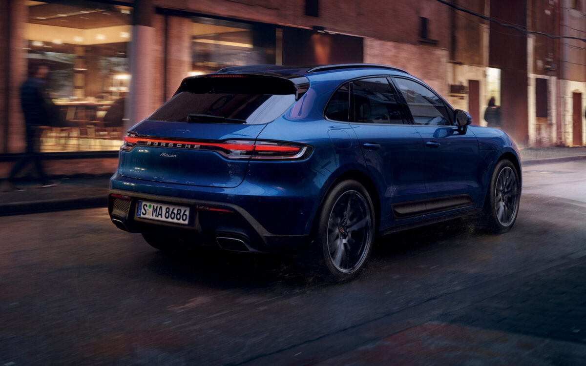 Blue Porsche Macan from the rear three-quarter at night on a lit street