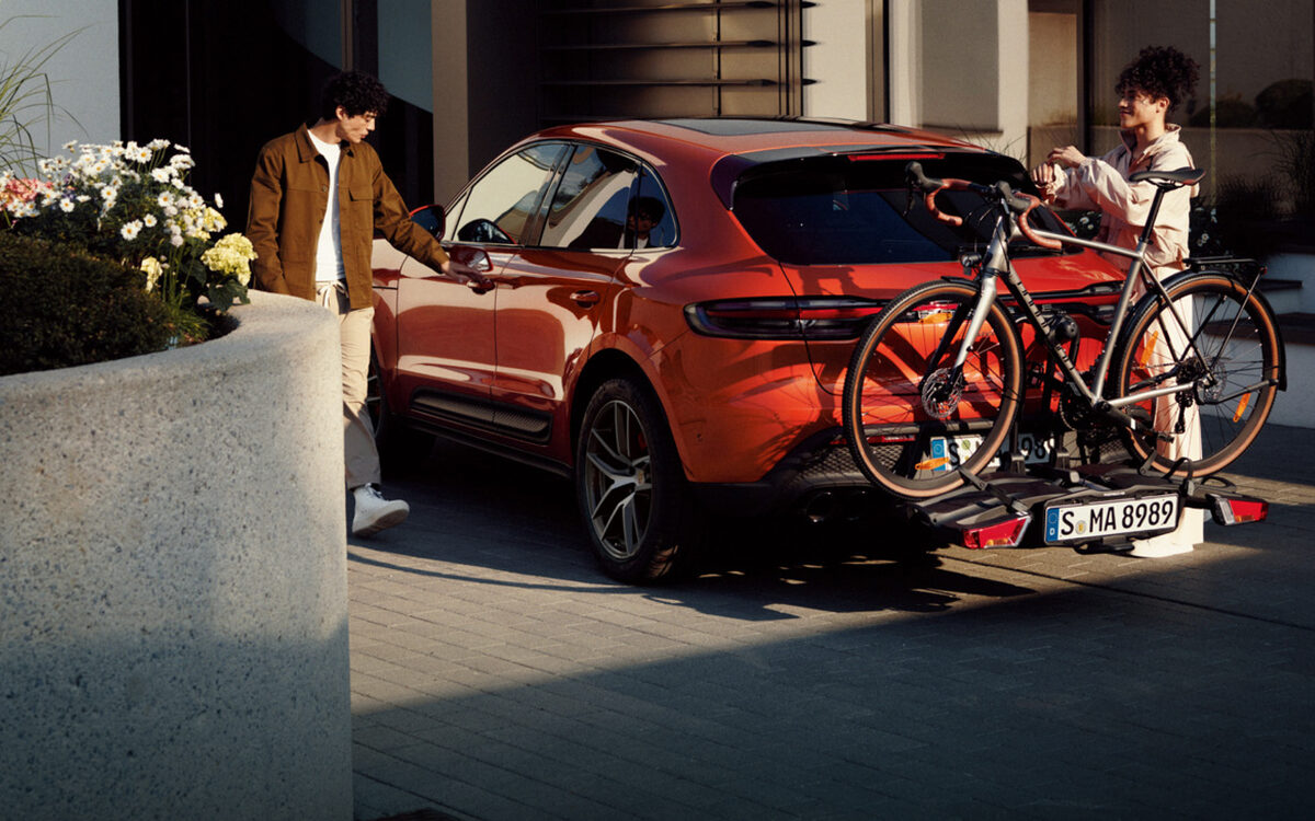 Orange Porsche Macan with a bicycle on the rear carrier outside a house