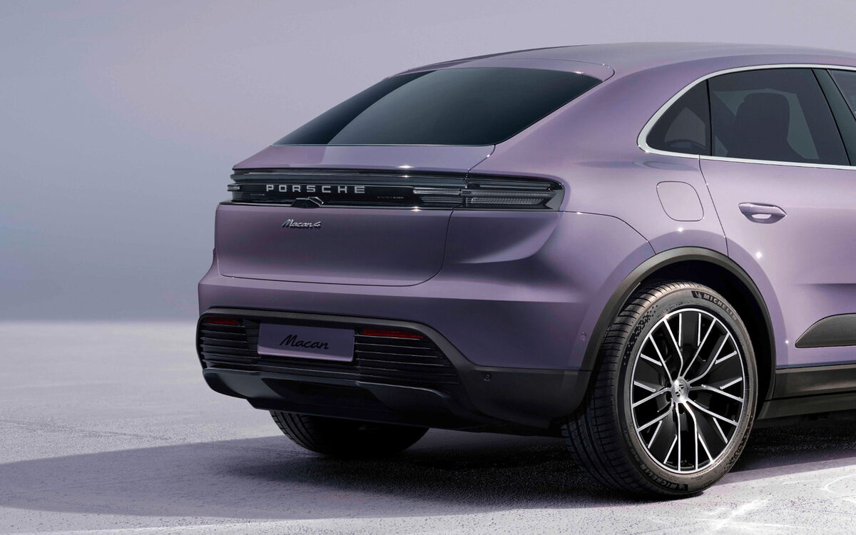 Porsche Macan Electric in lilac, rear three-quarter view showing the full-width light strip