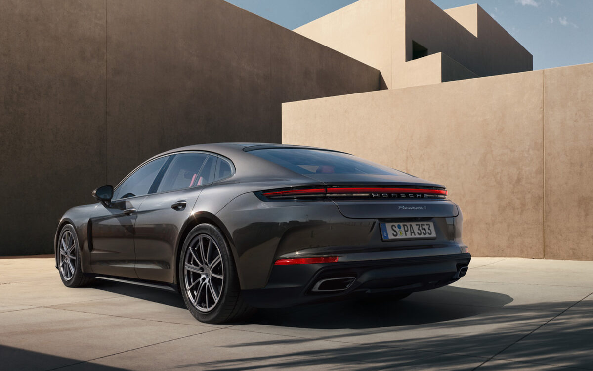 Dark grey Porsche Panamera, rear three-quarter view next to sandy walls