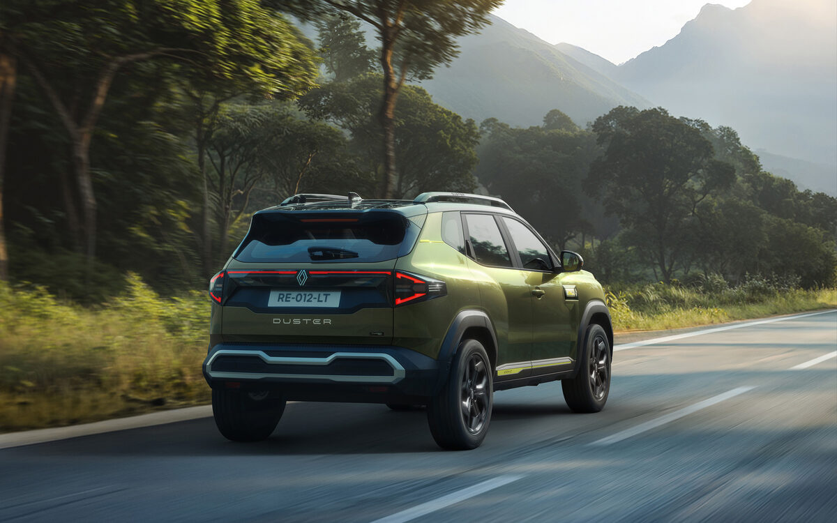 Green Renault Duster driving away on a forest road, rear three-quarter view