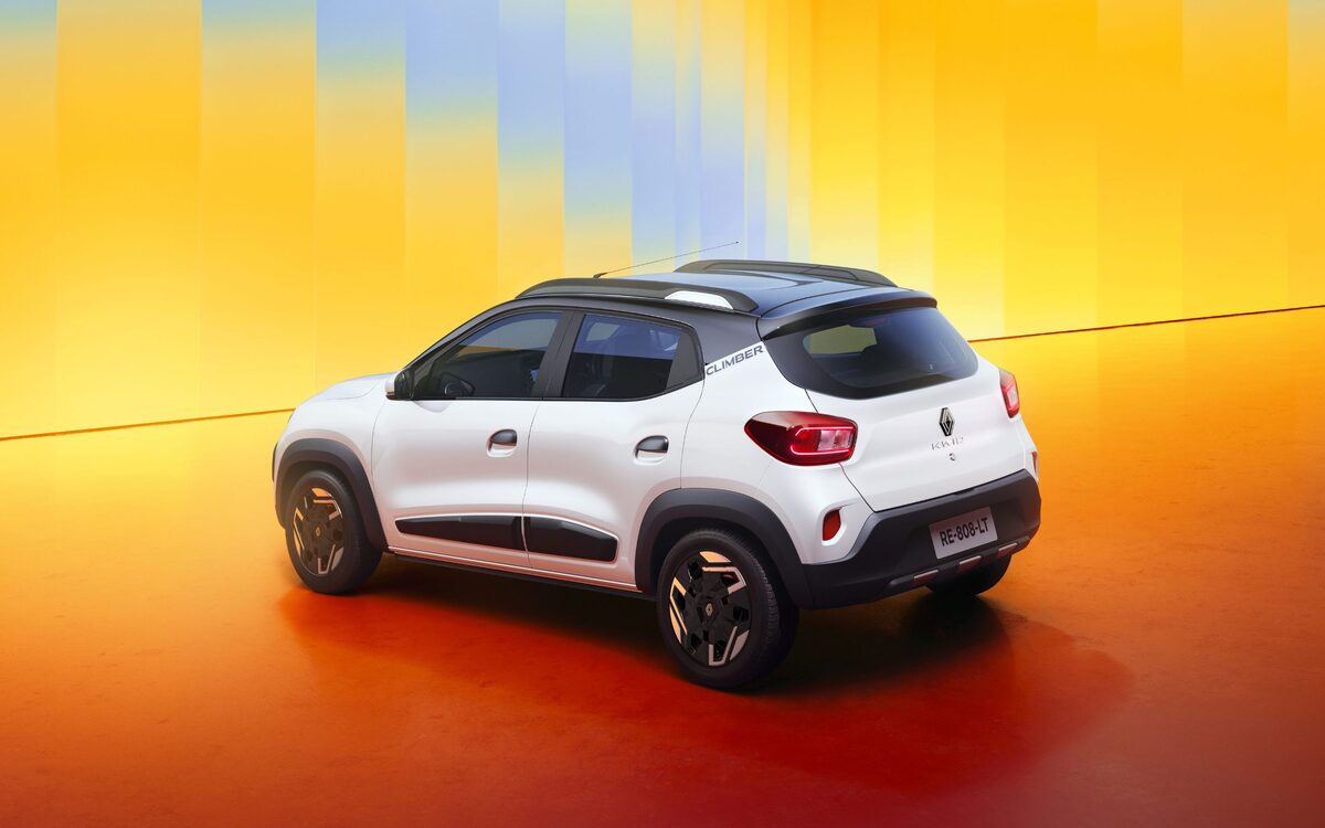 Renault Kwid Climber in white with black roof, rear three-quarter view against a warm gradient studio backdrop