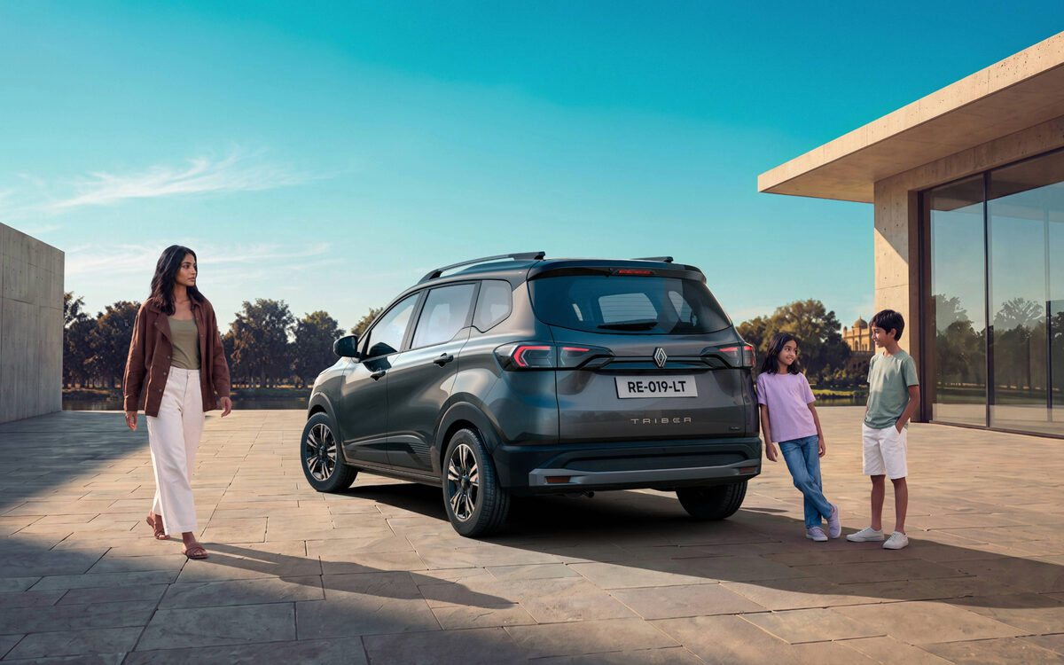 Renault Triber in grey parked beside a modern building with a family standing next to it