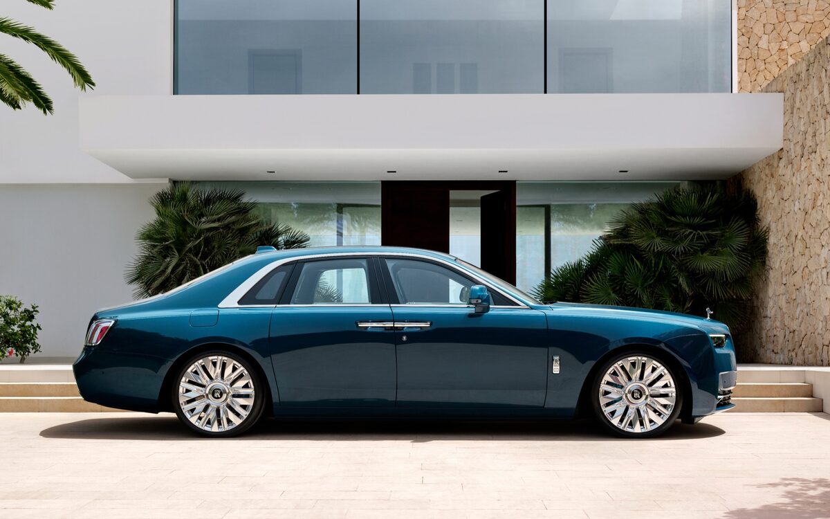 Rolls-Royce Ghost in teal, side profile outside a modern villa