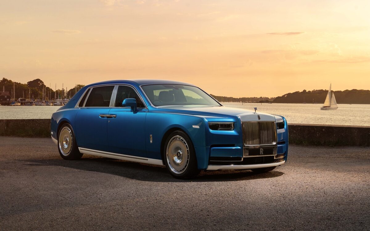 Rolls-Royce Phantom in blue parked by the water at sunset, front three-quarter view