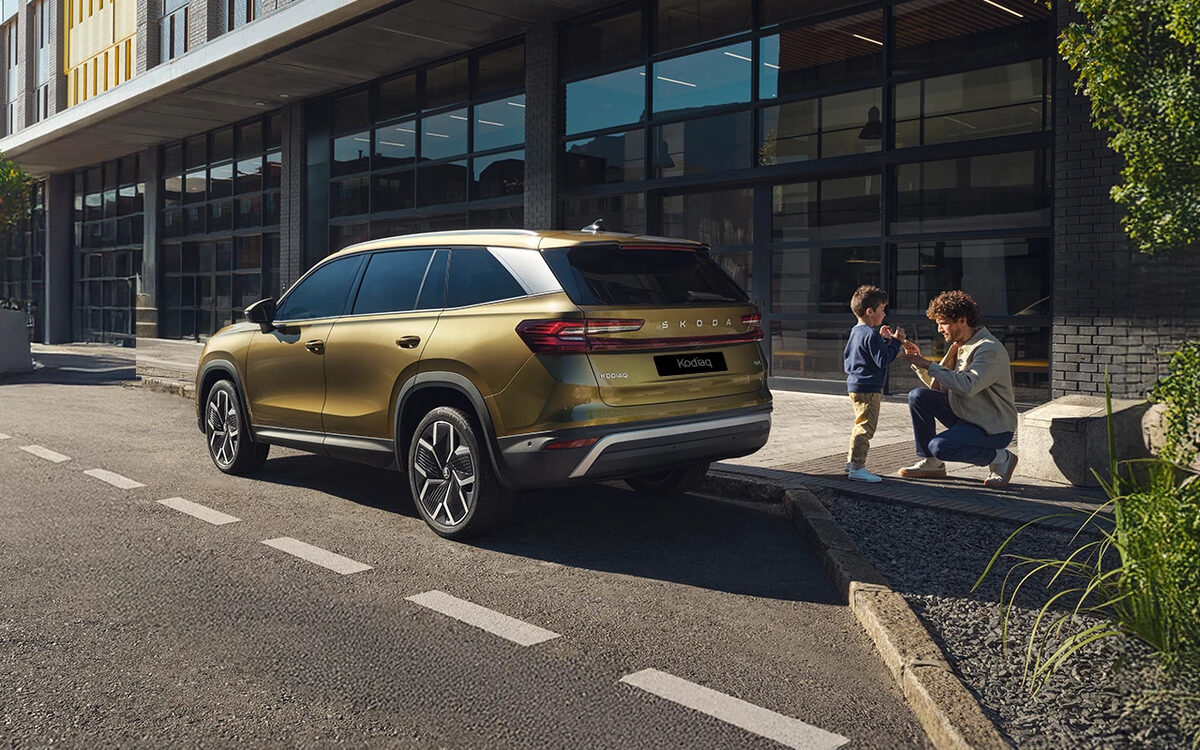 Skoda Kodiaq in Bronx Gold, rear three-quarter view parked on a city street outside a building