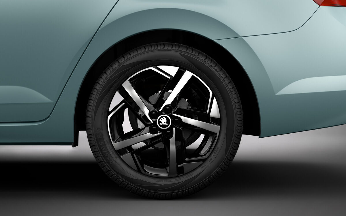 Close-up of the Skoda Slavia black and silver alloy wheel on a light blue body