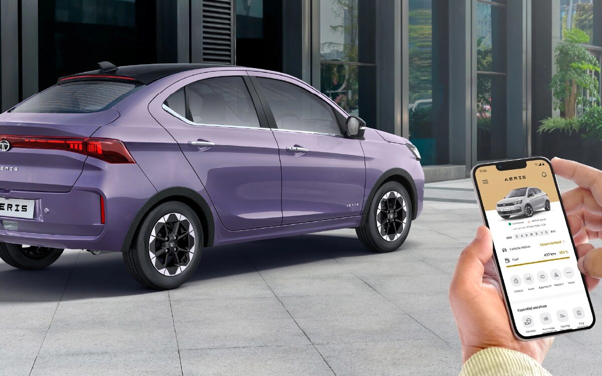 Tata Aeris in Dandeli Drizzle parked outside a building, rear three-quarter view, its owner holding the connected-car app
