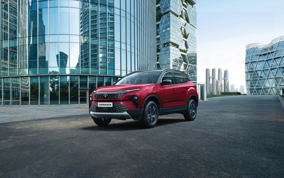 Tata Harrier in red with a black roof, front three-quarter view in front of glass office towers