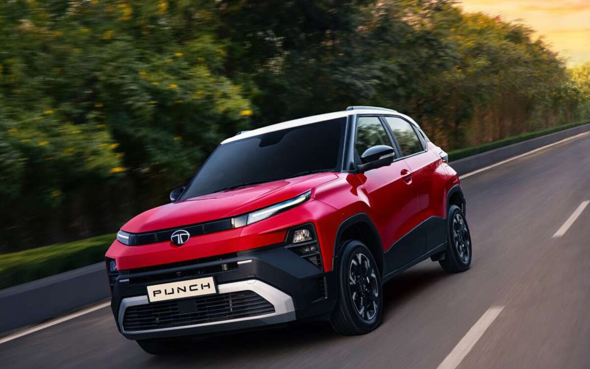 Tata Punch in red with a white roof, driving on a tree-lined road at sunset