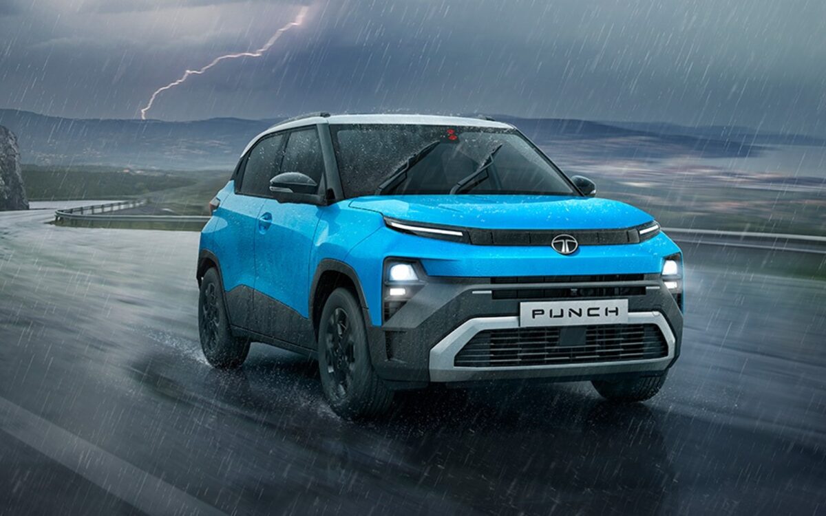 Tata Punch in blue, front three-quarter view driving on a wet coastal road in a thunderstorm