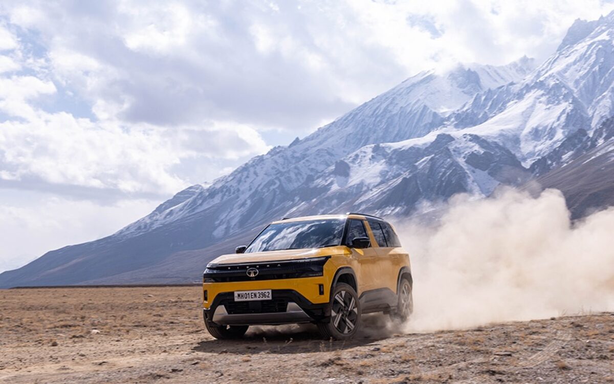 Tata Sierra kicking up dust on open ground below snow-capped mountains
