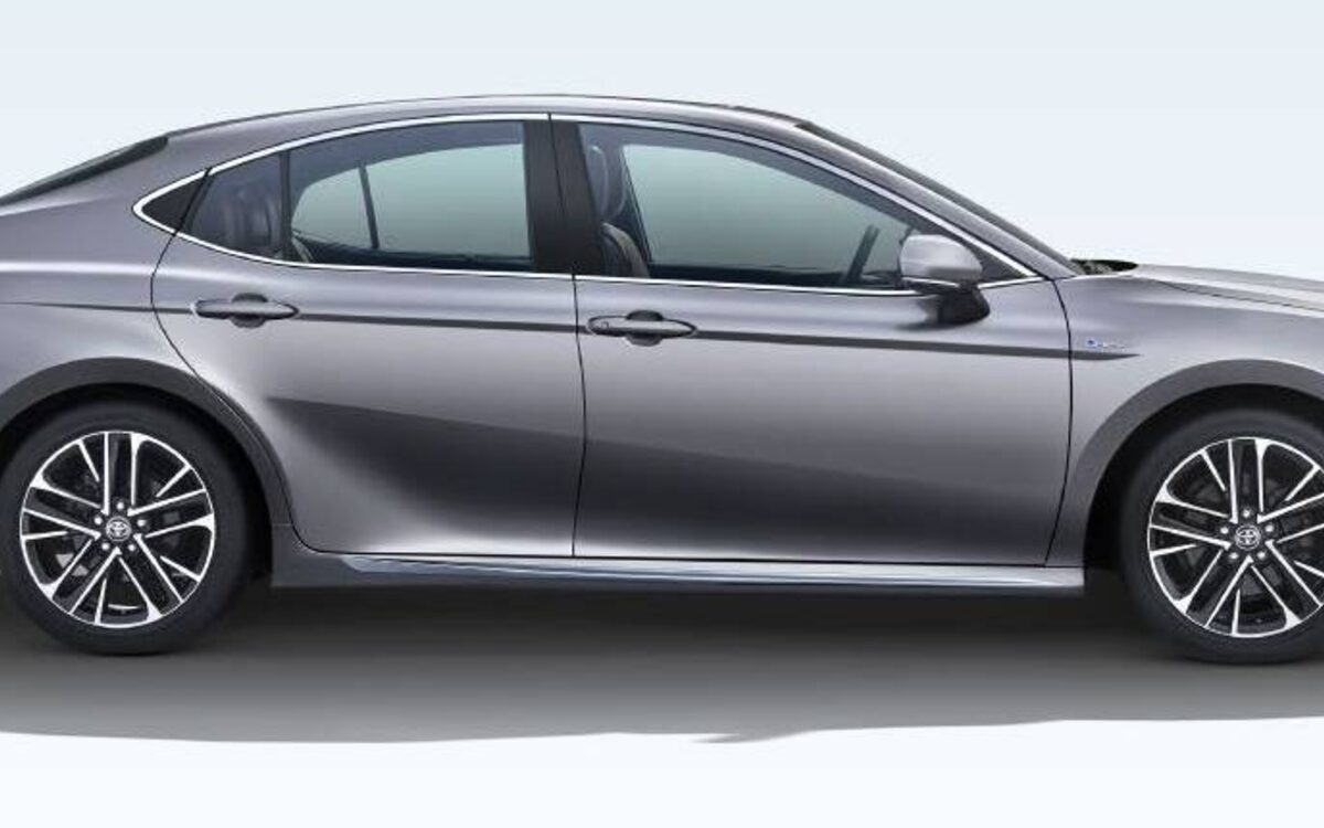 Grey Toyota Camry hybrid in side profile on a white studio background