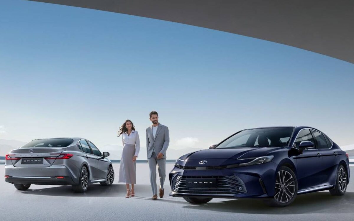 Dark blue and grey Toyota Camry hybrids parked under a curved canopy with a couple between them