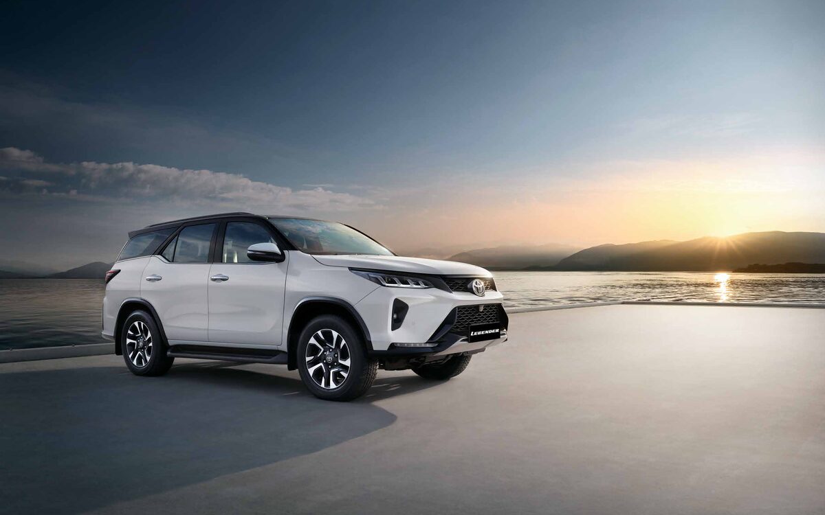 Toyota Fortuner Legender in white with black roof, side three-quarter view beside a lake at sunset