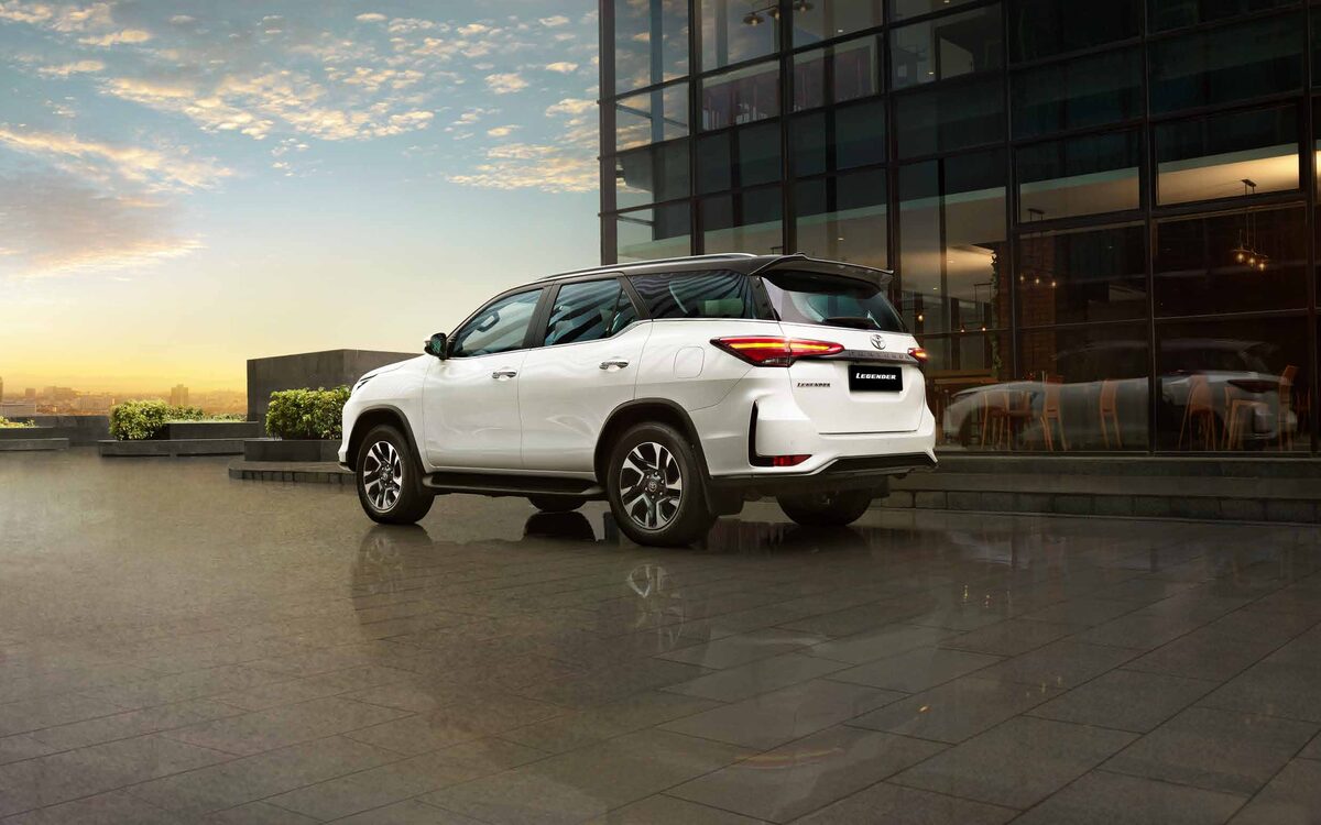 Toyota Fortuner Legender in white with black roof, rear three-quarter view outside a glass building