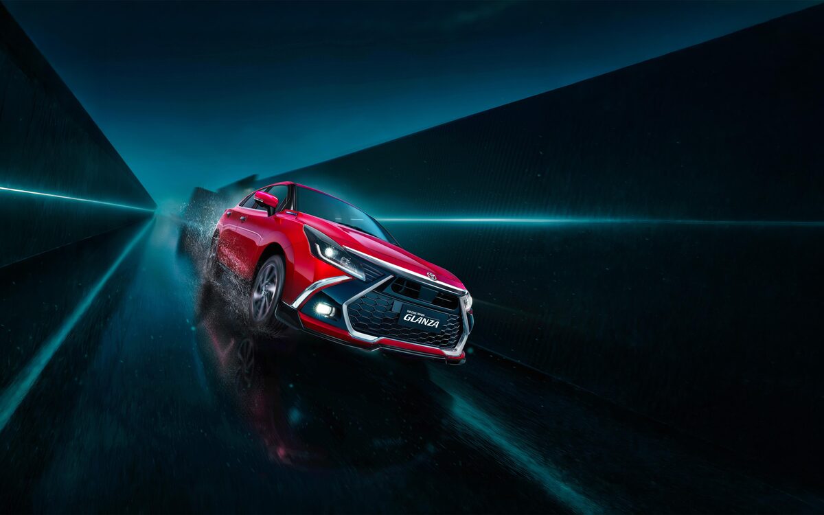 Toyota Glanza in red driving fast through a dark tunnel with a wet road