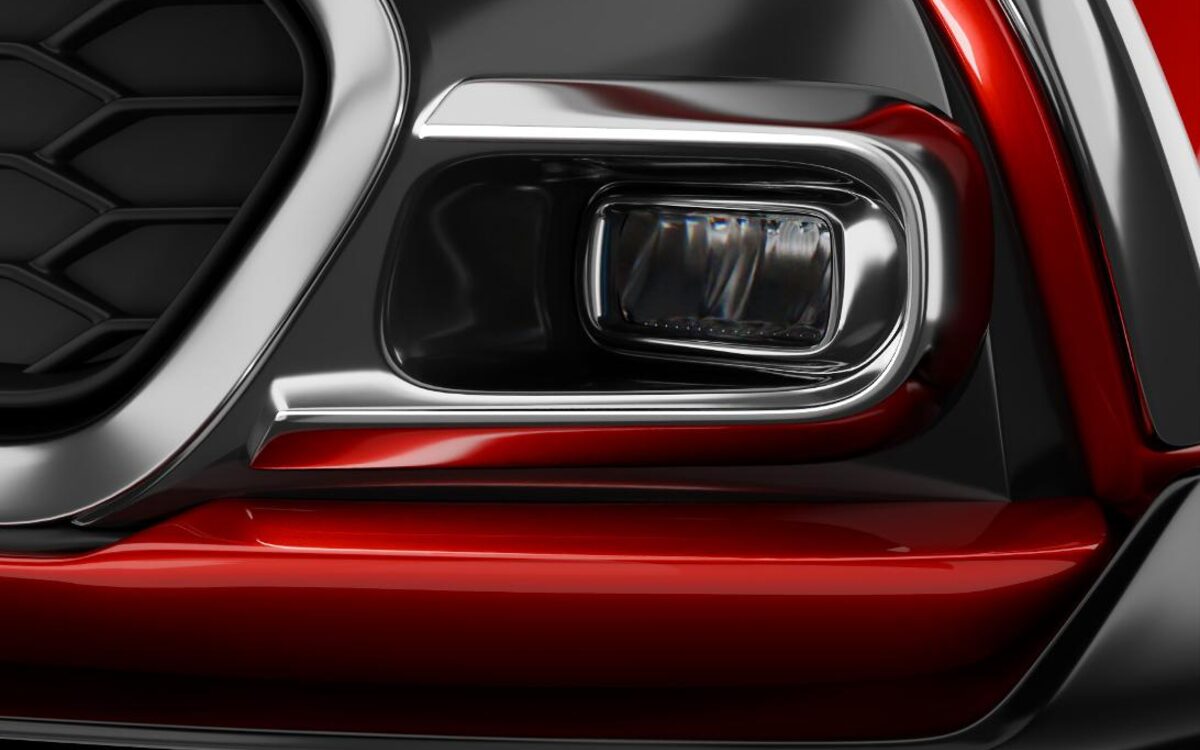 Close-up of the chrome-ringed fog lamp in the front bumper of a red Glanza
