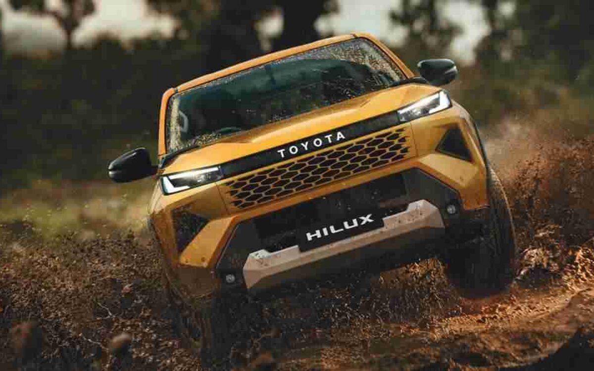 Toyota Hilux driving fast through mud on a forest trail, front view