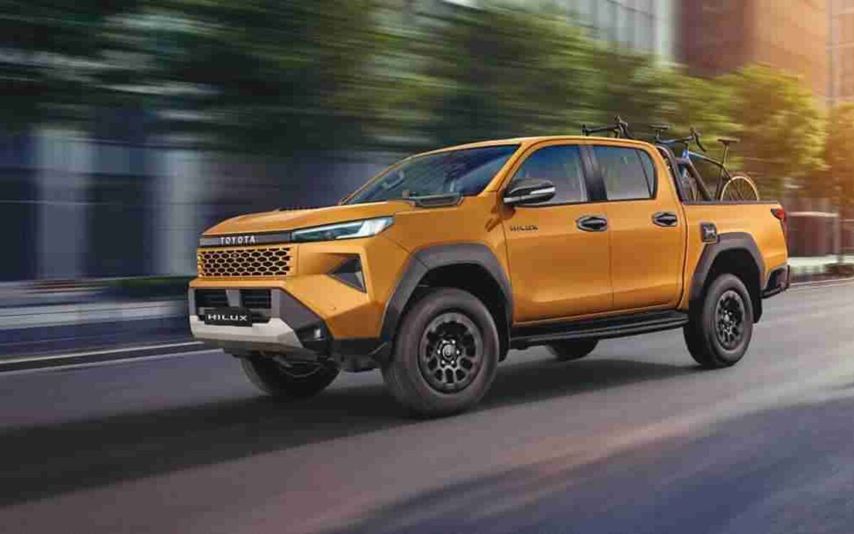 Toyota Hilux in Sulphur Metallic driving down a city street with a bicycle on the rear rack